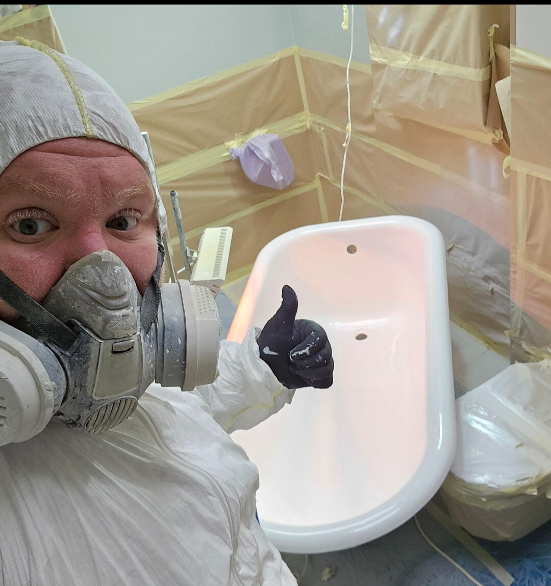photo of glossy baths owner photo of glossy baths re-enamelling owner Seamus with a thumbs up, in ppe, in a room full of masking up and a completed bath in Birmingham